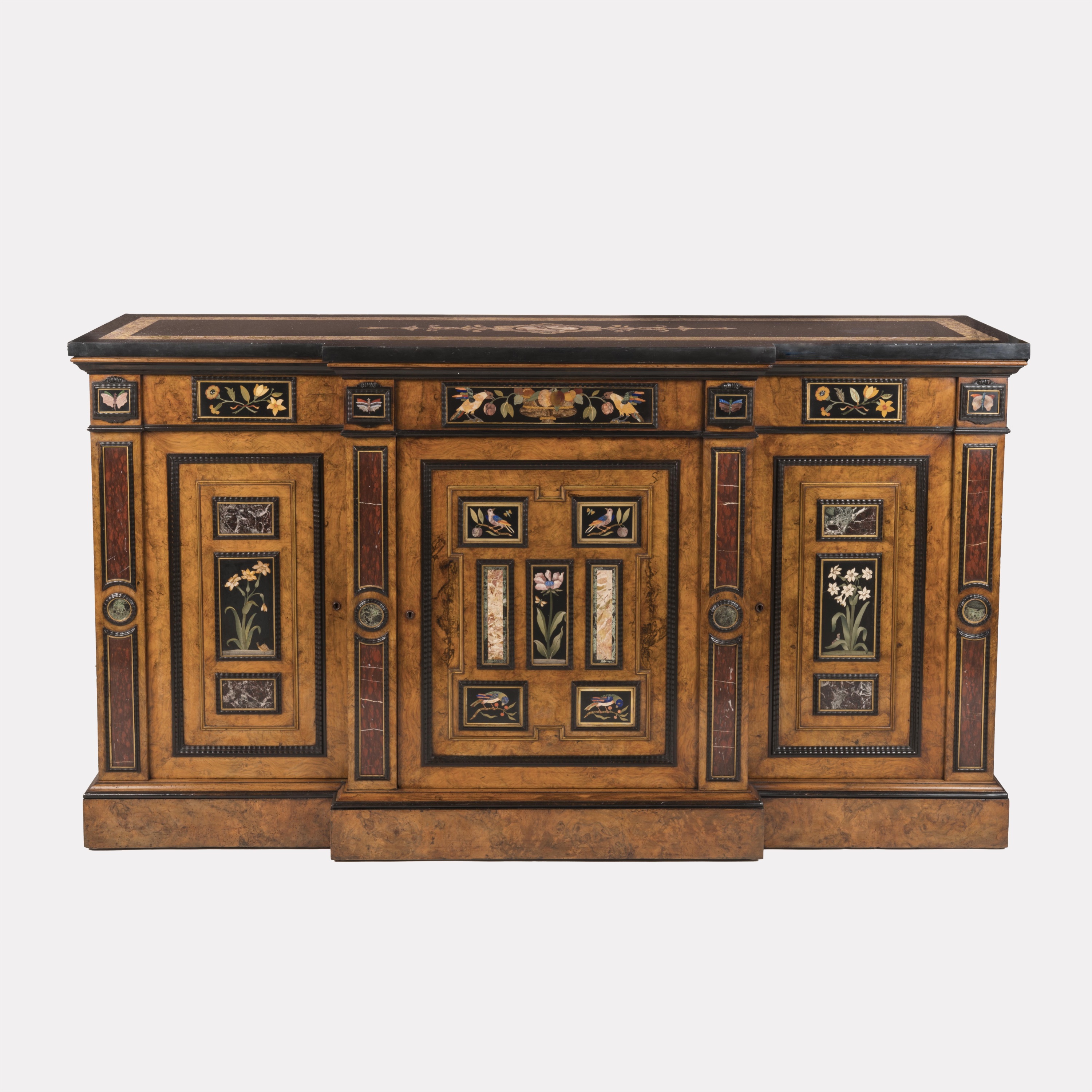 Burr walnut side cabinet featuring inset Pietra Dura panels of birds and flowers. The breakfront design includes three doors, a black marble top, and marble pilasters with classical specimen stone details.