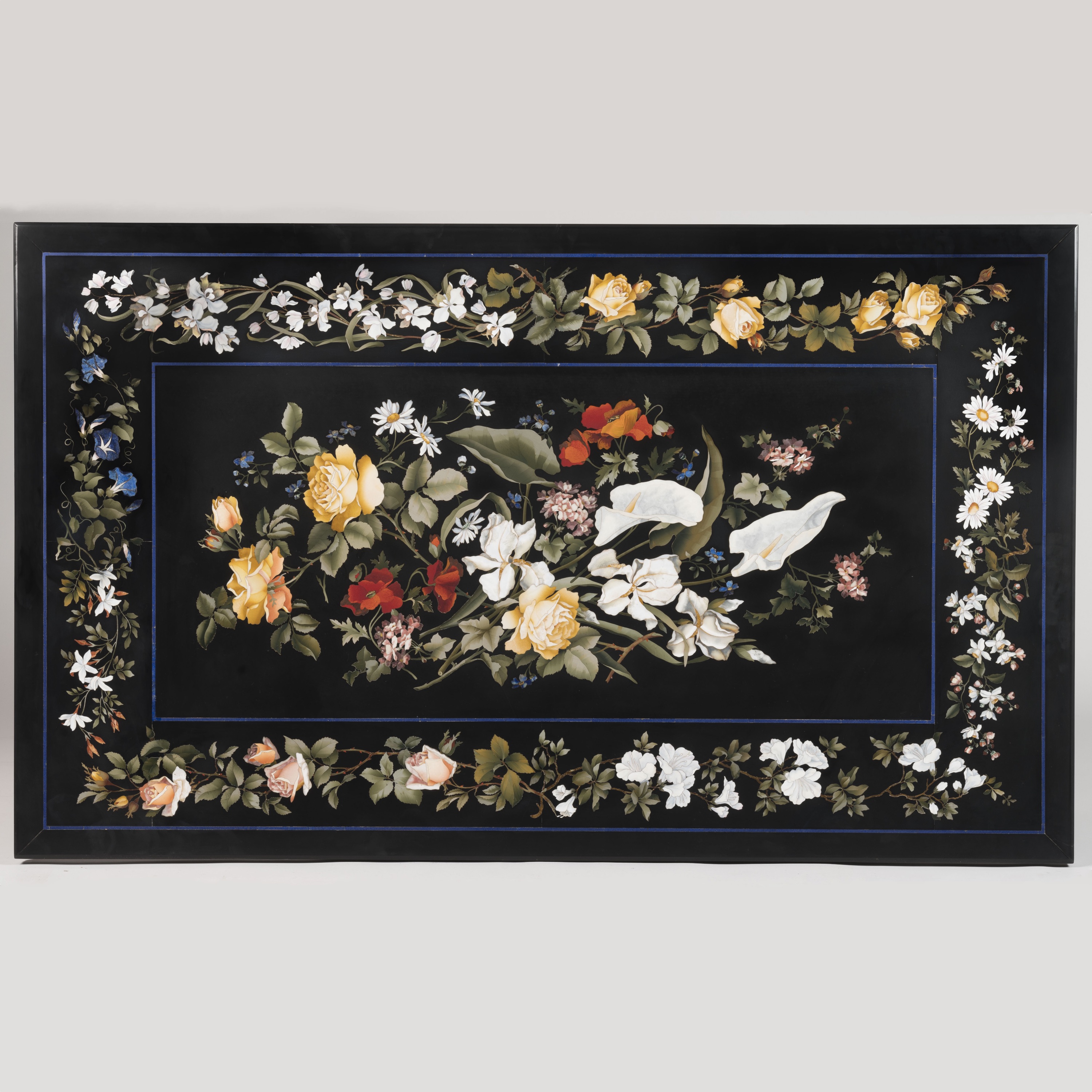 Rectangular black marble Pietra Dura tabletop featuring a vibrant central floral bouquet of lilies, roses, and daisies. A matching floral vine border with delicate blossoms and green leaves frames the piece.