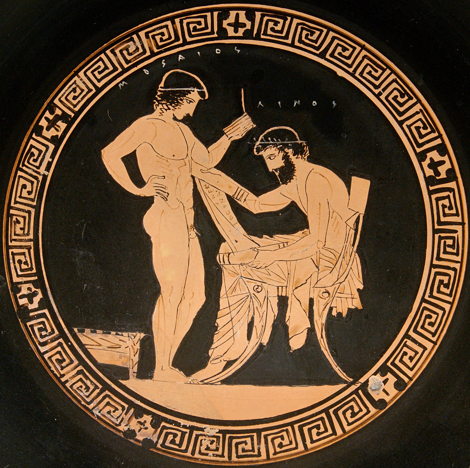 A circular Attic red-figure tondo from a Greek kylix (wine cup) depicting the mythological figures Linus and Musaeus. On the right, a bearded, seated Linus holds an open papyrus roll with Greek lettering, instructing the youthful, standing Musaeus. Both figures are rendered in terracotta orange against a solid black background, framed by an ornate geometric meander border.