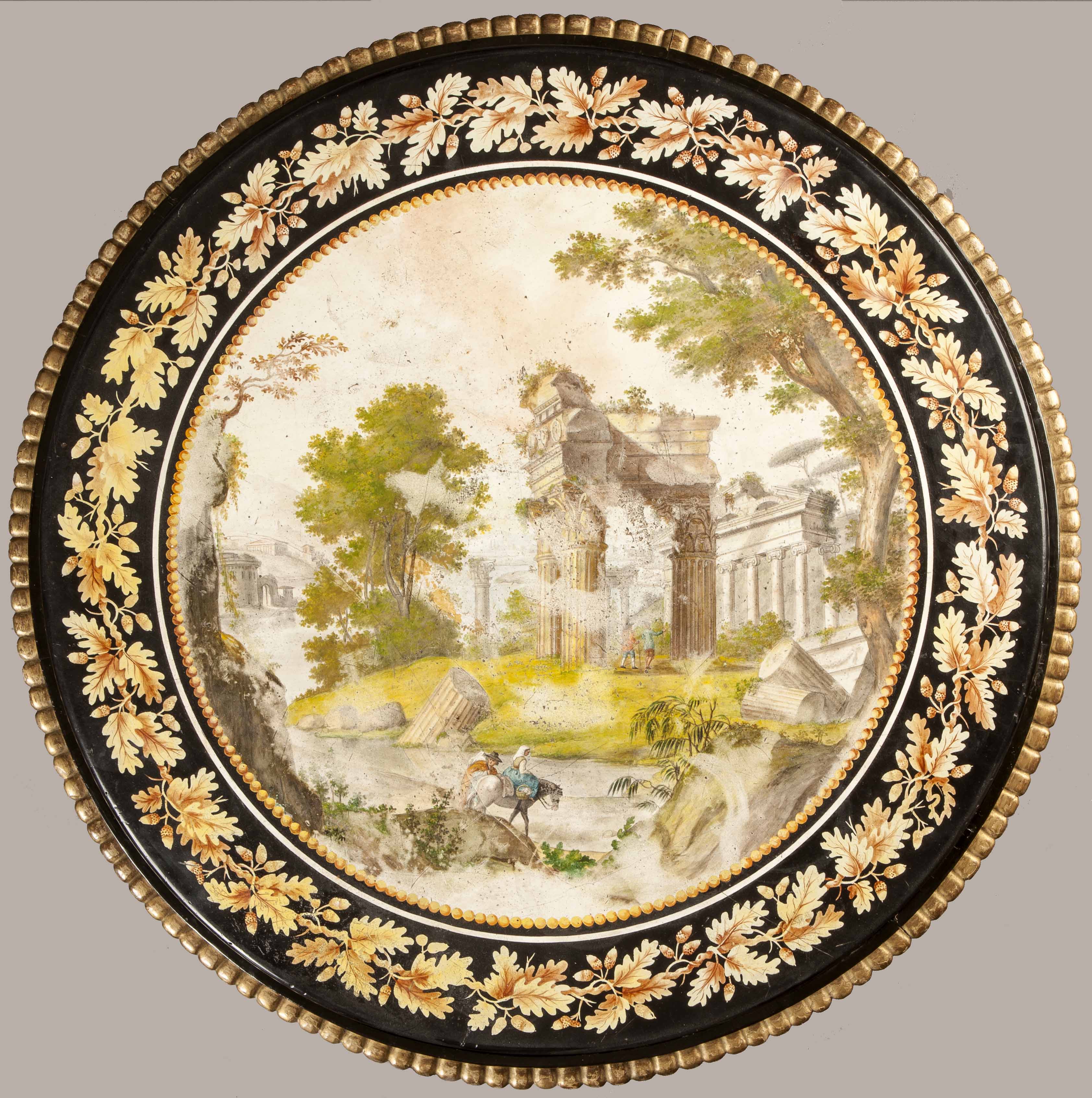 Circular Scagliola tabletop depicting classical Roman ruins and figures on horseback within a landscape. A black border with an oak leaf and acorn vine wreath surrounds the central scene.