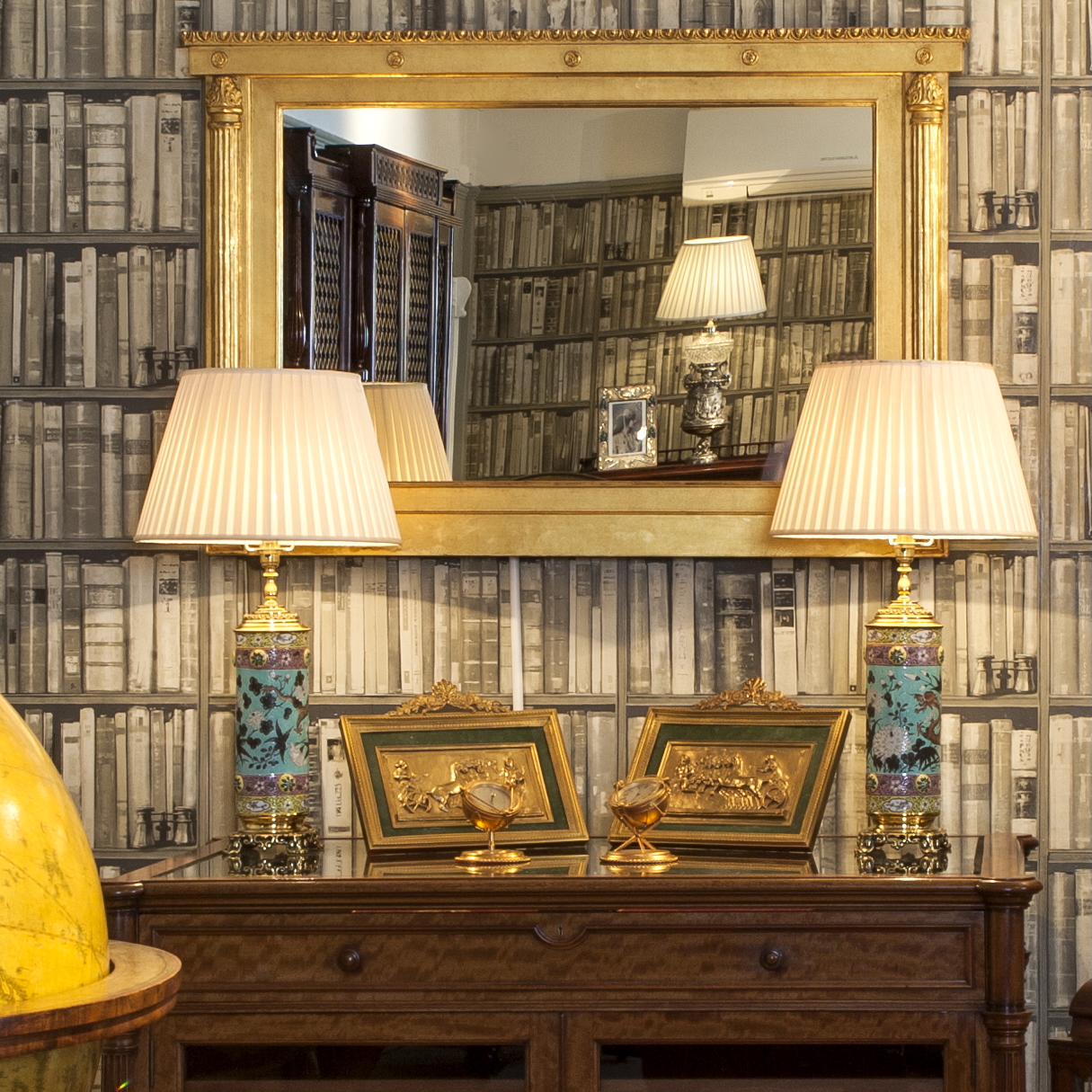 pair of antique Asian cloissonné enamel lamps at Butchoff Antiques, with a large English silvered banqueting lamp in the mirror reflection.